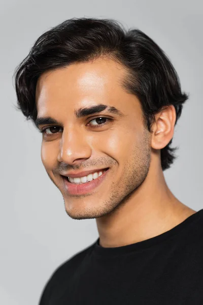 Молодий усміхнений чоловік в чорній футболці позує ізольовано на сірому — стокове фото