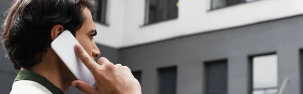 Young man talking on smartphone outside, banner — Stock Photo