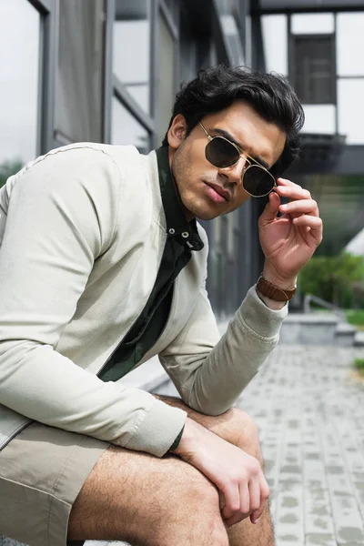 Stylish young man adjusting sunglasses outside — Stock Photo