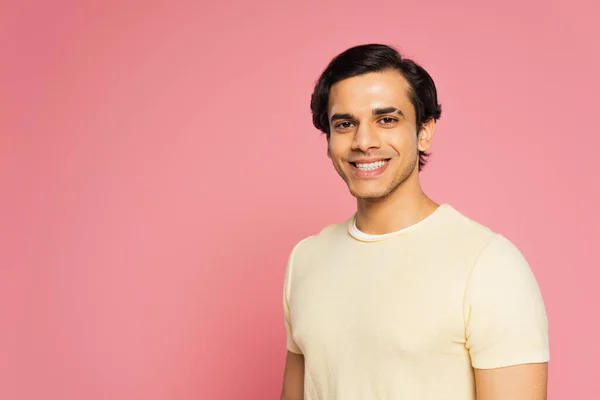 Щасливий молодий чоловік у білій футболці посміхається ізольовано на рожевому — стокове фото