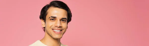 Heureux jeune homme regardant caméra et souriant isolé sur rose, bannière — Photo de stock