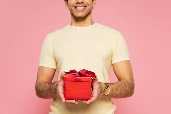 Vista cortada de homem alegre segurando caixa de presente vermelho isolado em rosa, banner — Fotografia de Stock