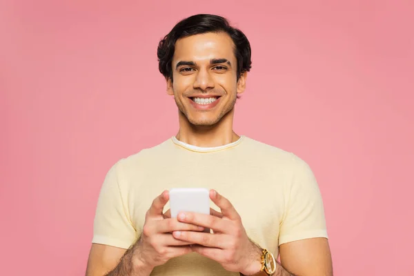 Joyeux jeune homme textos sur téléphone cellulaire isolé sur rose — Photo de stock