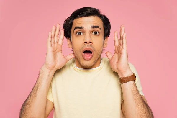 Shocked young man gesturing and looking at camera isolated on pink — Stock Photo