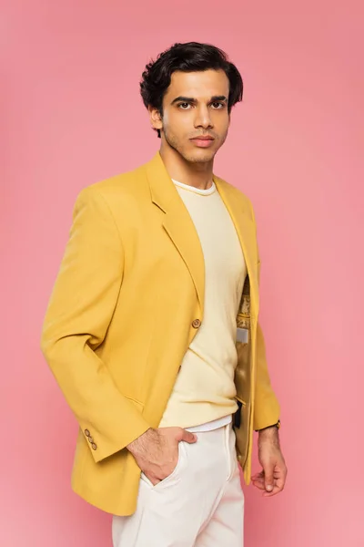 Young man in yellow blazer posing with hand in pocket isolated on pink — Stock Photo