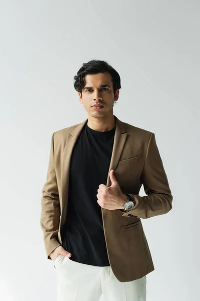 Young man in stylish beige blazer looking at camera isolated on grey — Stock Photo
