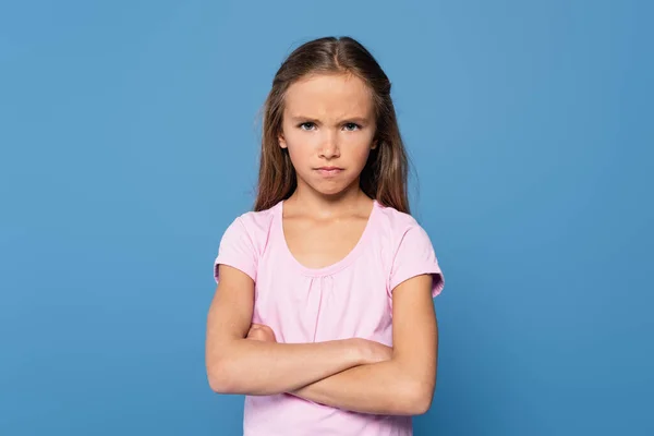 Offended girl with crossed arms looking at camera isolated on blue - foto de stock