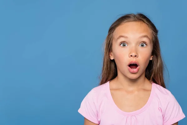 Astonished girl in pink t-shirt looking at camera isolated on blue — Stock Photo