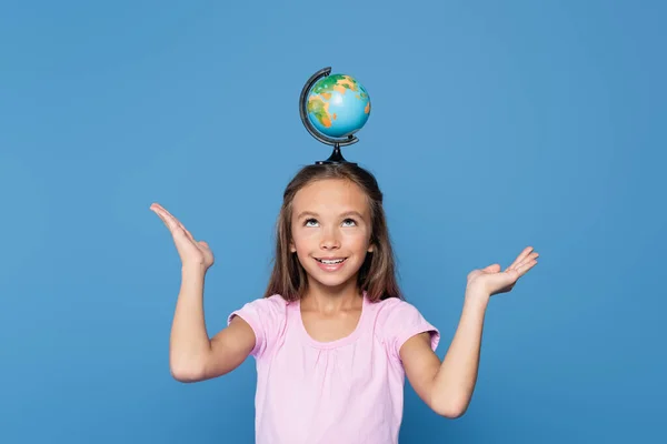 Happy kid holding globe on head isolated on blue - foto de stock