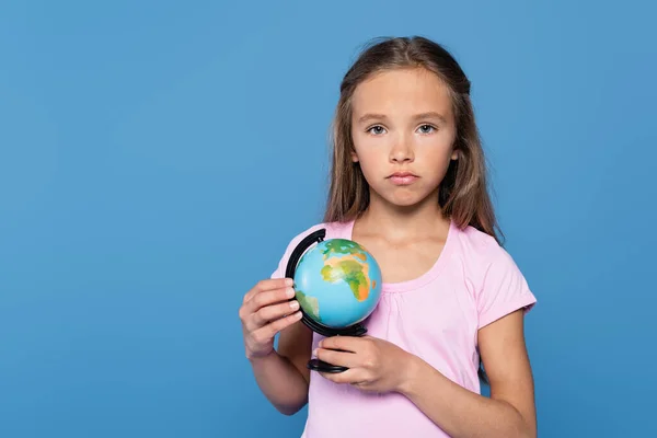 Verärgertes Kind mit Globus blickt isoliert auf Kamera auf blauem Grund — Stockfoto