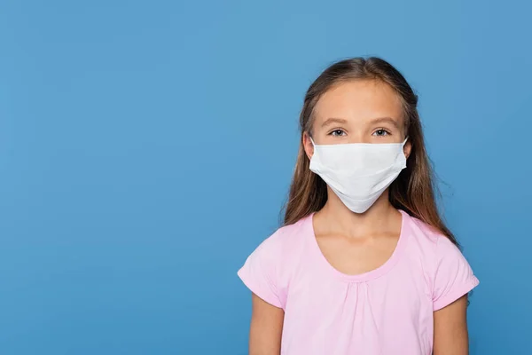 Girl in medical mask looking at camera isolated on blue - foto de stock