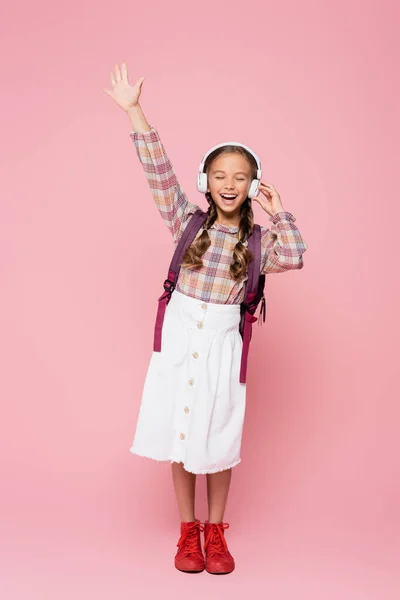 Schoolkid in headphones singing on pink background - foto de stock