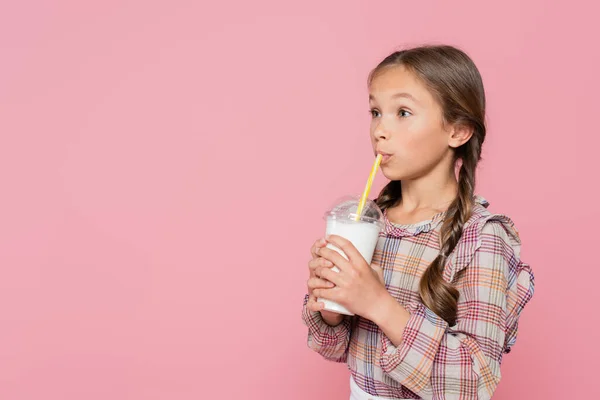 Ребенок в клетчатой рубашке пьет молочный коктейль, изолированный на розовый — стоковое фото