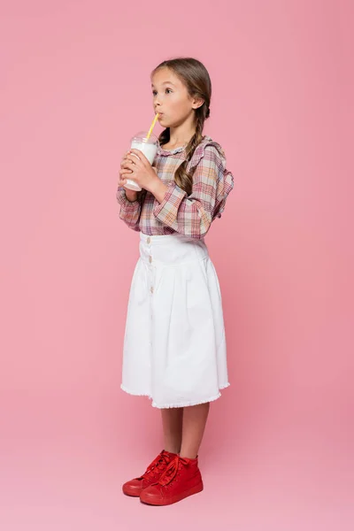Menina pré-adolescente elegante bebendo milkshake no fundo rosa — Fotografia de Stock