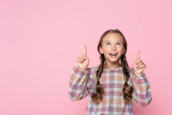 Cheerful kid in checkered blouse pointing up with fingers isolated on pink — Stock Photo