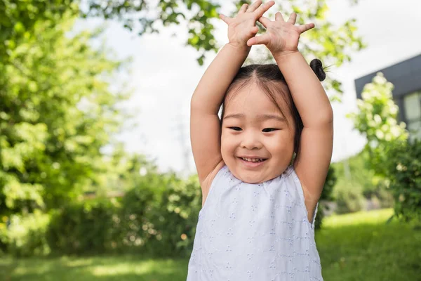 Joyeux asiatique gosse debout avec levé les mains à l'extérieur — Photo de stock