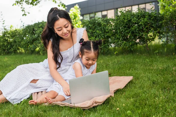 Glücklich asiatische Mutter und Tochter beobachten Film auf laptop in park — Stockfoto