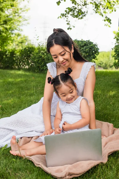 Sorrindo asiático mãe e filha assistindo filme no laptop no parque — Fotografia de Stock