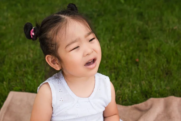 Alto angolo vista di bruna asiatico bambino con bocca aperta seduta su picnic coperta — Foto stock