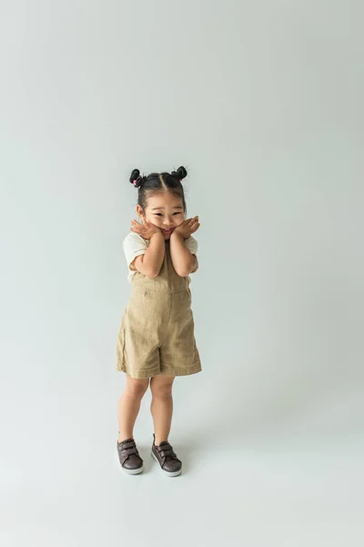 Повна довжина щасливої азіатської дівчинки-малюка позує на сірий — стокове фото