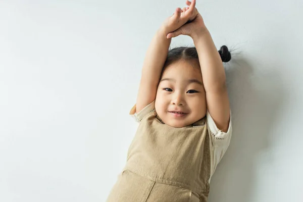 High angle view of cheerful asian toddler girl posing on grey — Stock Photo
