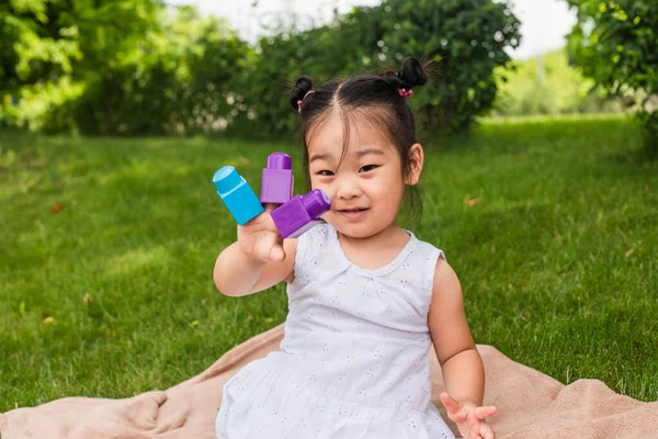Smiling asian toddler child in dress playing building blocks — Stock Photo