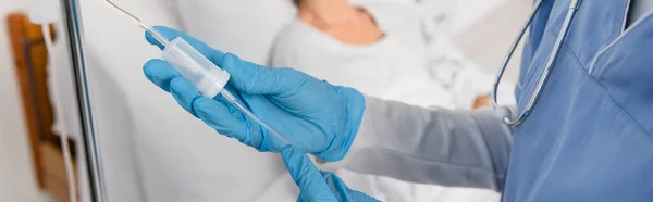 Vista recortada de la enfermera sosteniendo el tubo de la estación de terapia intravenosa en la sala de hospital, pancarta - foto de stock