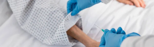 Vista cortada de enfermeira segurando cateter perto paciente sênior em fundo turvo, banner — Fotografia de Stock