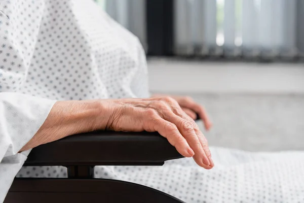 Vista ritagliata della donna anziana che indossa abito paziente in sedia a rotelle — Foto stock