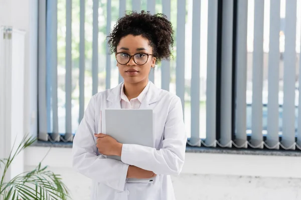 Afrikanisch-amerikanischer Arzt im weißen Kittel mit Papiermappe — Stockfoto