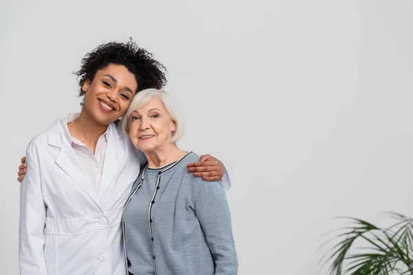 Allegro medico afro-americano che abbraccia il paziente anziano — Foto stock