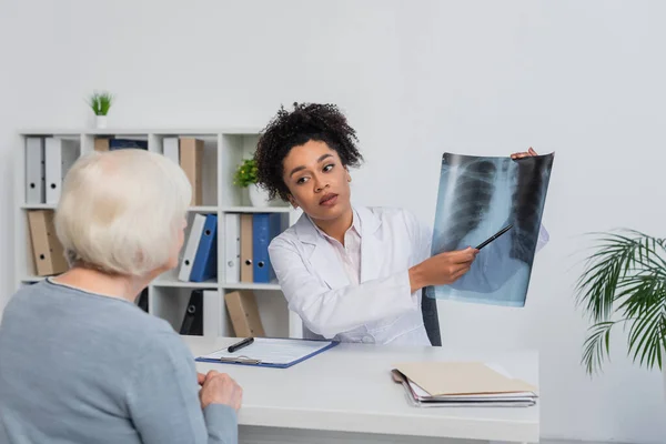 African american doctor pointing at fluorography near senior patient — Stock Photo