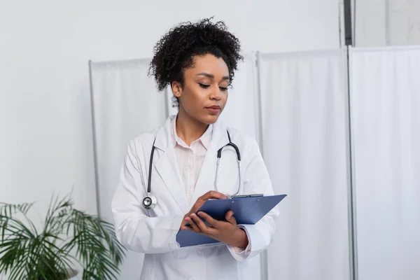 Afrikanisch-amerikanischer Arzt schaut Klemmbrett im Krankenhaus an — Stockfoto