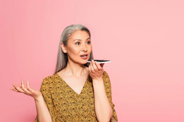 Стильна азіатська жінка з сірим волоссям, що надсилає голосове повідомлення ізольовано на рожевому — стокове фото