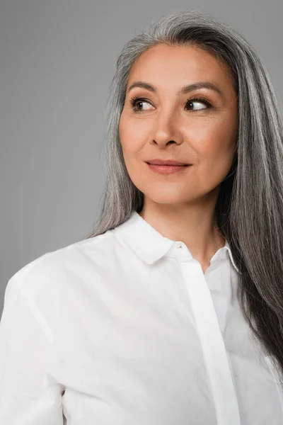 Porträt einer reifen asiatischen Frau mit grauen Haaren, die zur Seite schaut und isoliert auf grau lächelt — Stockfoto