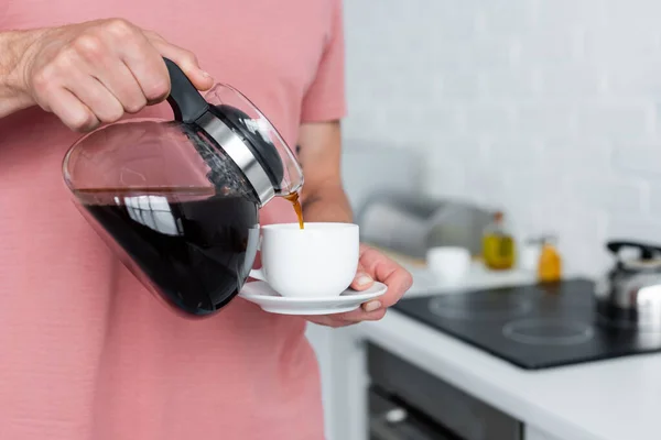Обрезанный вид человека, наливающего кофе в чашку дома — стоковое фото