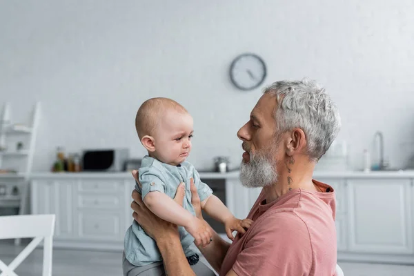 Man holding upset baby daughter at home — Stock Photo