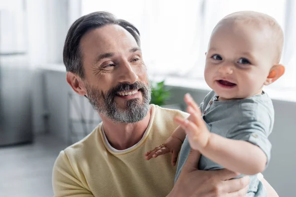 Lächelnder Mann hält kleine Tochter zu Hause — Stockfoto