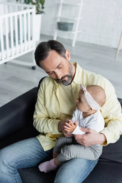 Hombre sosteniendo bebé hija en las manos en la sala de estar - foto de stock