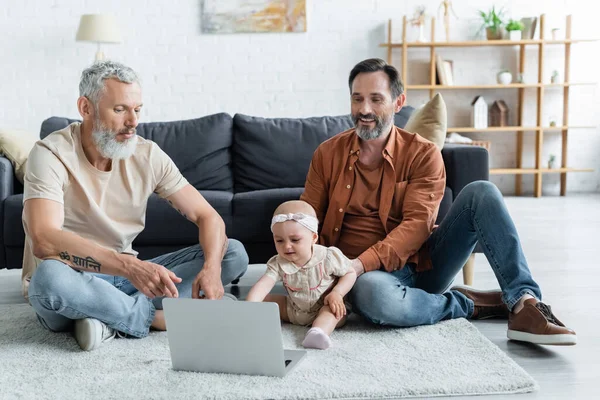Sorrindo homossexual homem sentado perto da filha, laptop e parceiro — Fotografia de Stock