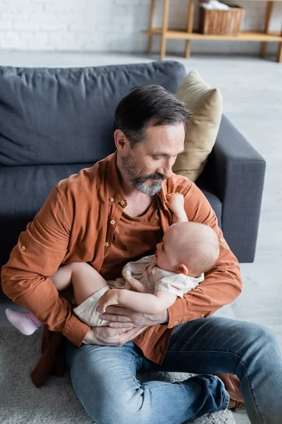 Зрілий чоловік тримає дочку малюка у вітальні — стокове фото