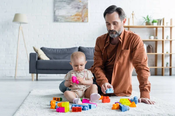 Padre jugando bloques de construcción de colores con hija pequeño - foto de stock