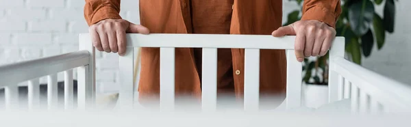 Cropped view of man standing near baby bed, banner — Stock Photo