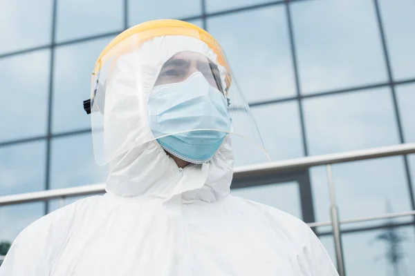 Visão de baixo ângulo do trabalhador médico em terno hazmat e viseira de segurança ao ar livre — Fotografia de Stock