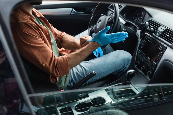 Cropped view of driver wearing latex gloves in car — Stock Photo