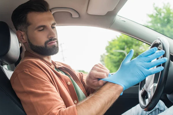 Young driver wearing latex glove in car — Stock Photo