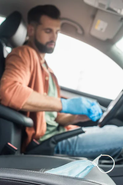 Masque médical en voiture près du conducteur flou en gants de latex — Photo de stock
