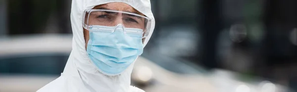 Trabajador médico en máscara protectora y gafas mirando a la cámara al aire libre, pancarta - foto de stock