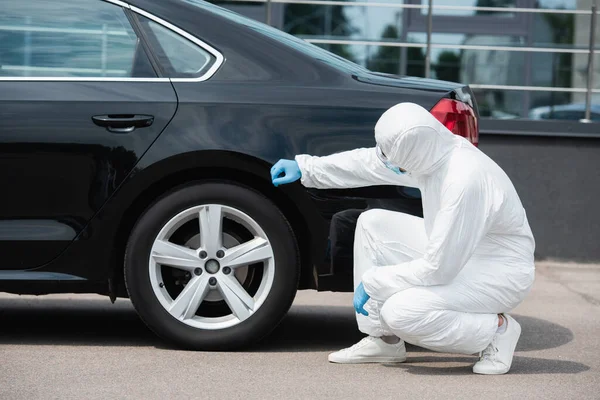 Border guard in hazmat suit and latex gloves checking car outdoors — Stock Photo