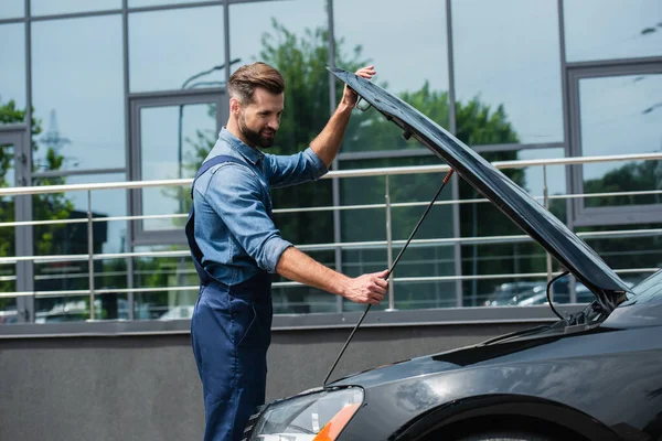 Lächelnder Mechaniker öffnet Motorhaube von Auto im Freien — Stockfoto